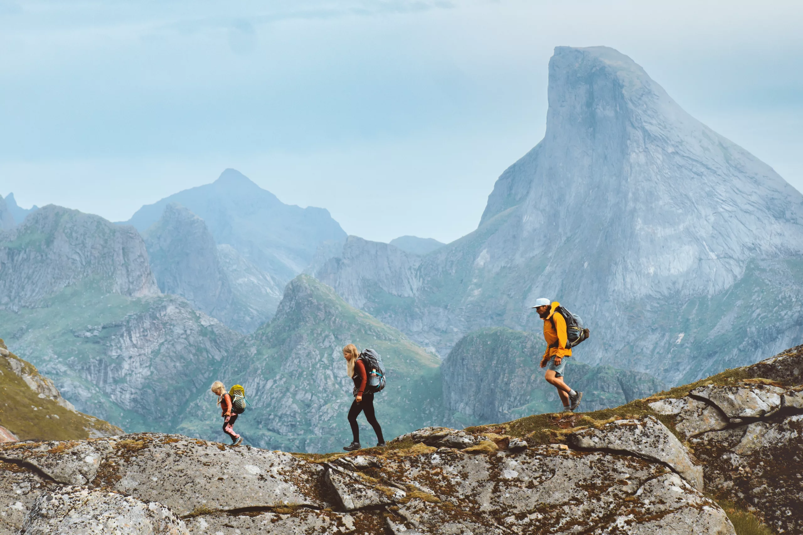 A family together on vacation walking along the ridge of a dramatic mountain range, illustrating the time you could free up to enjoy with your family when you have a your business financial planning worries in good hands.