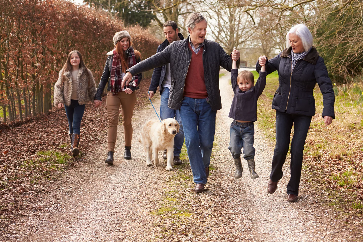 A happy family of many generations enjoys a fall walk together, illustrative of the worry-free time you can spend with your family when your finances are managed by liminal.