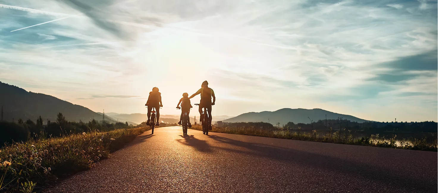 3 happy family members ride their bikes into the sunset, to illustrate the happy moments you can enjoy with your family when your daily financial worries and strife are handled by a firm like Liminal Partners.
